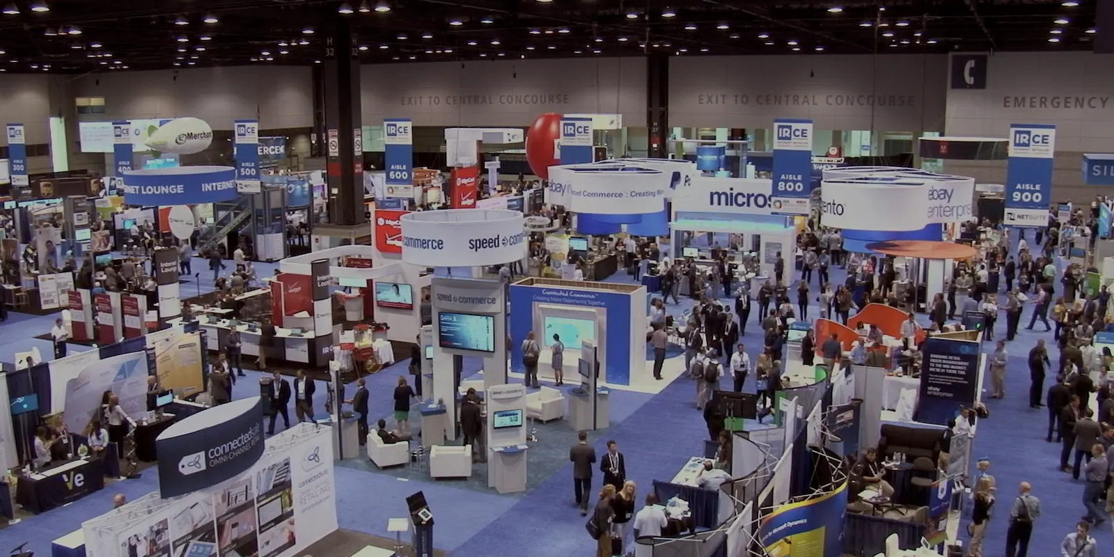 Crowd moving through an exhibition hall with booths and displays